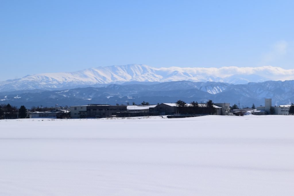 広がる雪原の奥に大きな雪山が聳える風景
