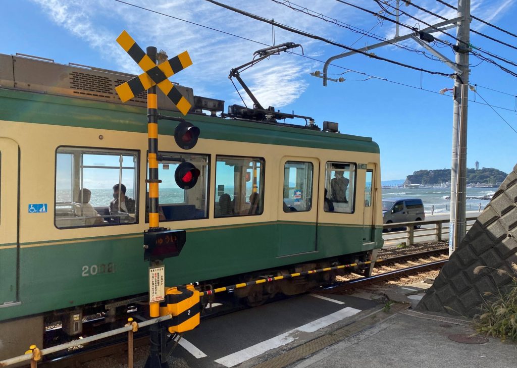 腰越の踏切を通過する江ノ電