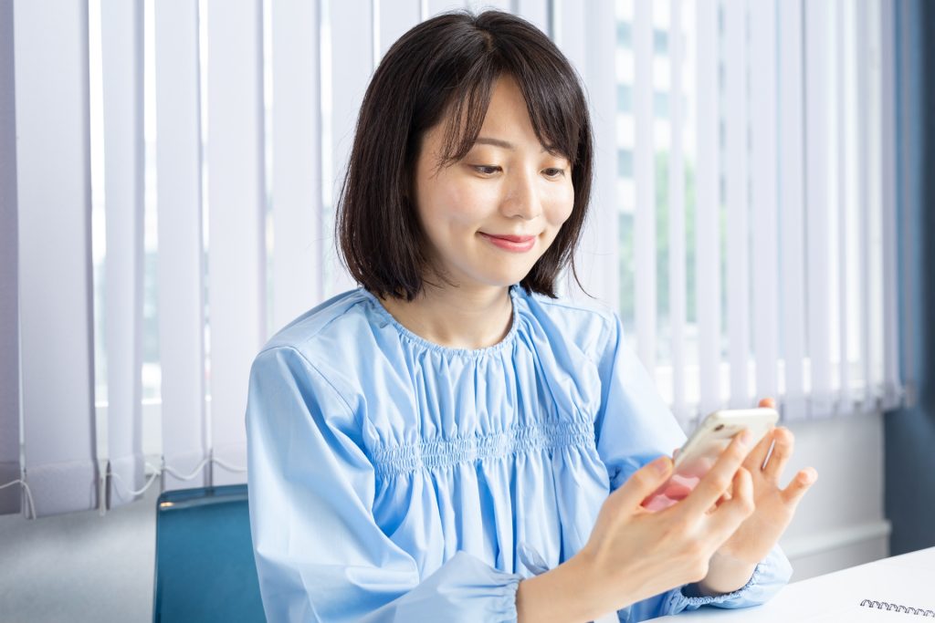 PCを開きスマホを操作する女性03の様子