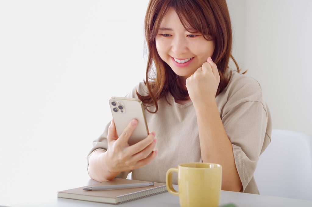 スマホを見て喜びの表情を浮かべる若い女性の様子