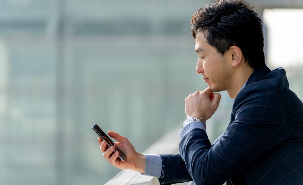 スマホを見て考える男性ビジネスマンの様子