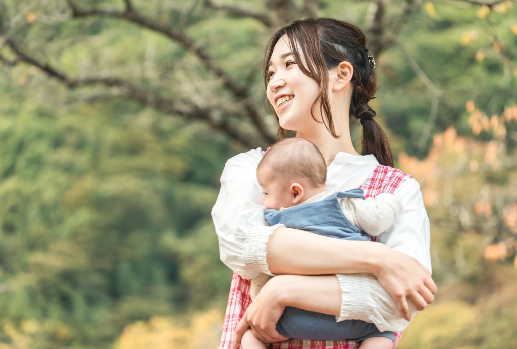秋の公園を散歩するベビーシッターの女性の様子