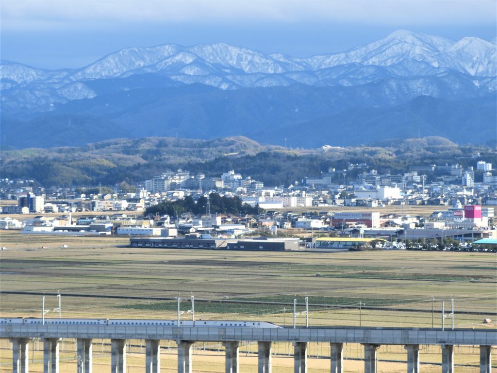 加賀平野を疾走する北陸新幹線と田舎の風景の様子
