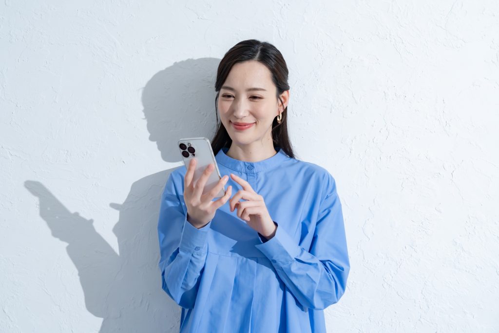 携帯を触る青いワンピースを着た女性の様子