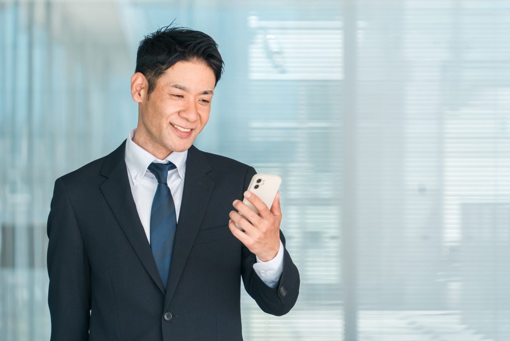 オフィスでスマホを使うビジネスマンの様子
