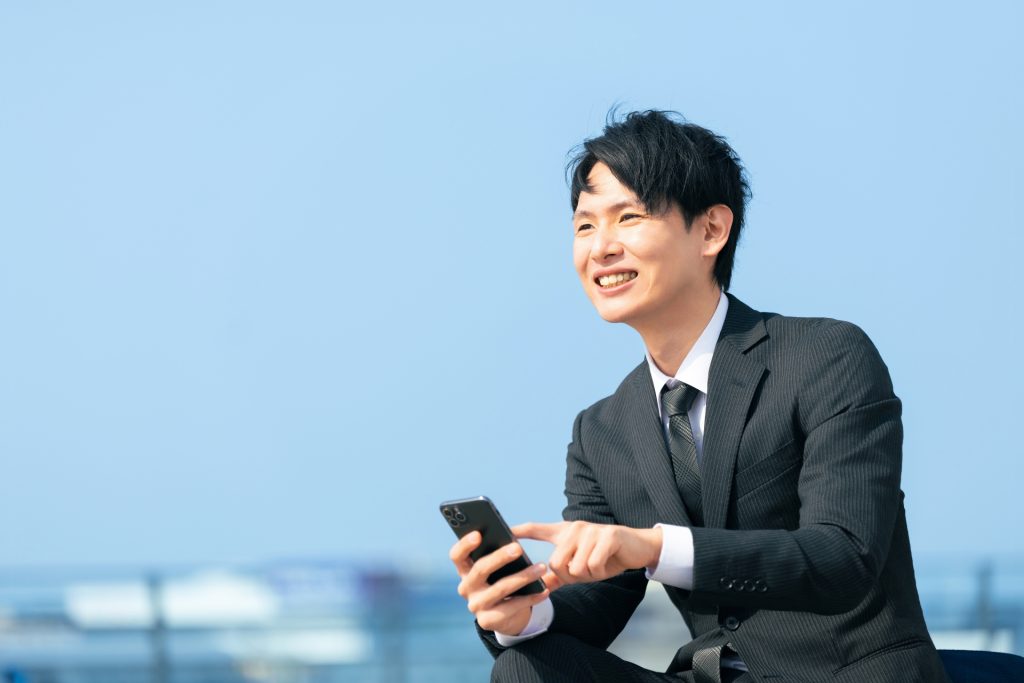 スマホを使う笑顔の男性ビジネスマンの様子