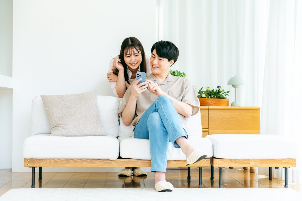 リビングでスマホを見るカップルの様子