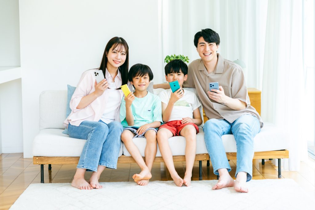 スマホを持ってソファに座る家族の様子