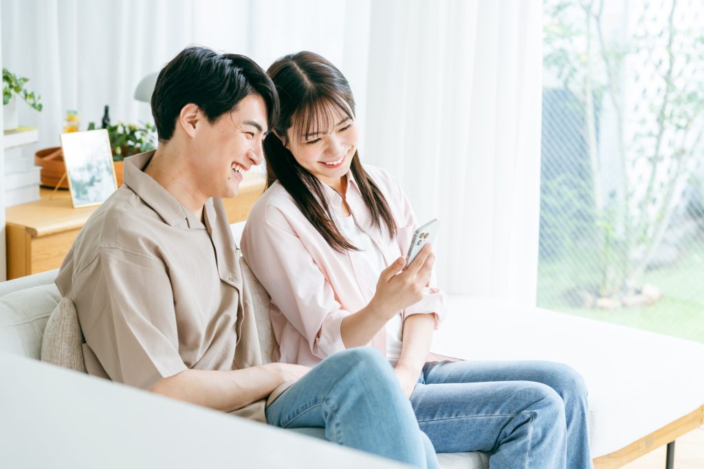 リビングでスマホを見るカップルの様子