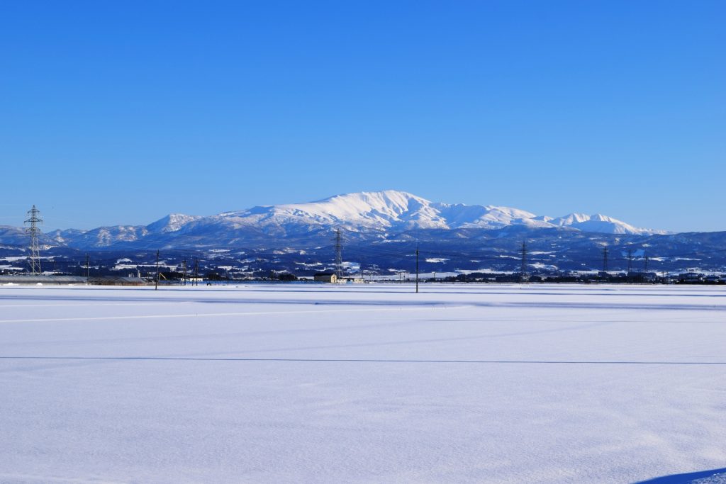広がる雪原の奥に大きな雪山が聳える風景